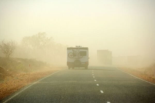 Sandstorm - a hugh sandstorm sweeps over a road in the outback. Cars are almost invisible because of the dense sand clouds - Northern Territory, Australia
