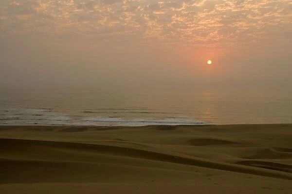 Sun setting over the Atlantic ocean - with dunes in the foreground - Dune Fields - Namib Desert - Namibia - Africa
