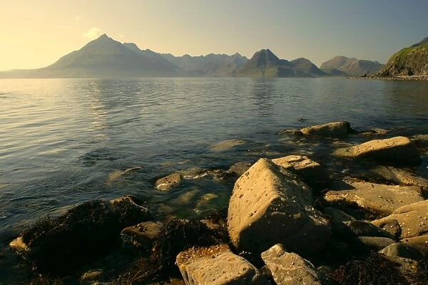 Sunset at beach near Elgol with boulders in foreground and jagged Cuillin mountains in background Elgol, Isle of Skye, Western Highlands, Scotland, UK