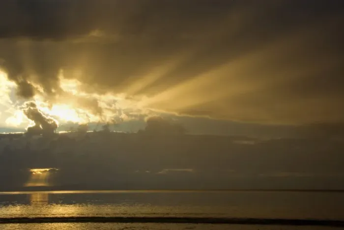 Framed Print : Thunderstorm over the ocean - dark clouds of a thunderstorm are approaching the beach at Oyster Bay. The setting sun is able to breack through gaps in the dense cloud cover and sends orange and yellow sunrays out