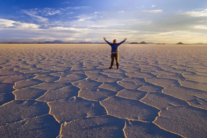 Framed Print : Traveller on Salar de Uyuni - a happy woman with raised hands stands amidst polygonal salt pattern on dried up salt lake at sunset - Salar de Uyuni - Altiplano - Bolivia - South America