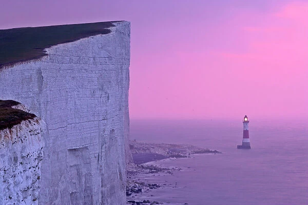 UK - lighthouse at Beachy Head with steep chalk cliffs at sunrise. East Sussex, England, UK