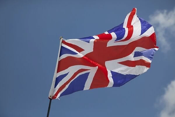 Union Jack flag - flying in light breeze against blue sky - UK
