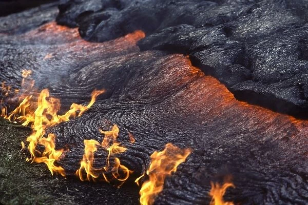 USA - Hawaii - Big Island - Eruption of the Pu'u O'o Vent - a vent of the Kilauea Volcano - Advancing lava flow - close up - molten lava creeping under the rapidly cooling upper crust - small flames are from grass burning