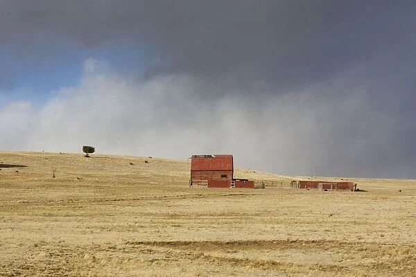 USA - old barn on New Mexico Prairie with approaching storm. New Mexico in January