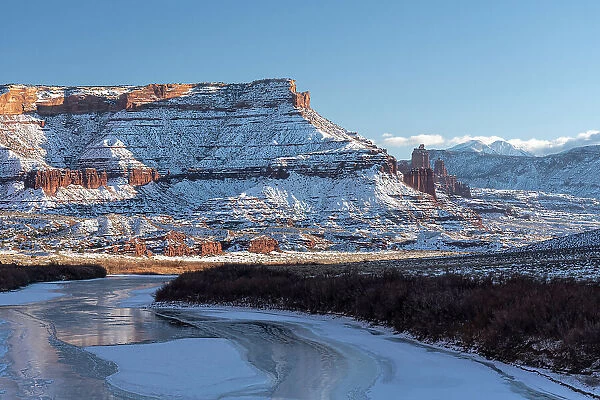USA, Utah. Fisher Towers, La Sal Mountains, and canyon walls reflected in the icy Colorado River. Date: 05-01-2021