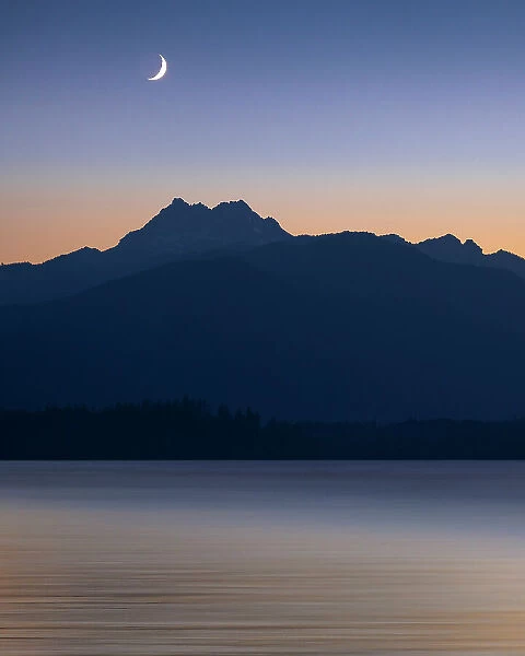 USA, Washington State, Seabeck. Crescent moon at sunset over Hood Canal and Olympic Mountains. Date: 13-07-2021