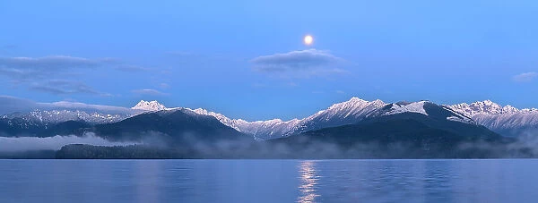 USA, Washington State, Seabeck. Panoramic of moon setting over Olympic Mountains and Hood Canal. Date: 29-01-2021