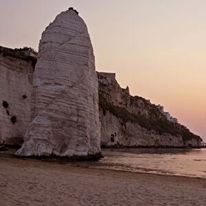 Beach of Vieste with chalk cliffs and symbol Pizzomunno at sunrise Gargano Peninsula, Italy