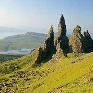 Mountain scenery rolling green slopes and bizarre rock formation Old Man of Storr seen from above with view towards Sound of Raasay Isle of Skye, Western Highlands, Scotland, UK