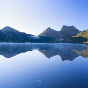 Mountain scenery - stunning Dove Lake in front of massive Cradle Mountain is one of Tasmania's most beautiful and famous natural features. In early morning there is still mist on the calm waters of Lake Dove