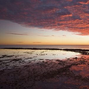Ningaloo sunset - gorgous sunset over Ningaloo Reef and ocean. Brilliantly red ablaze clouds reflect in the calm surface of remaining water in rock pools - Ningaloo Reef Marine Park, Western Australia, Australia