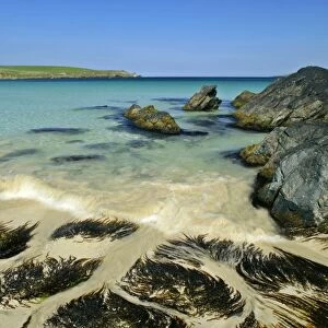 Summer beach approaching wave, blue sea, rocks and white sand at beach of Scousburgh Sands South Mainland, Shetland Isles, Scotland, UK