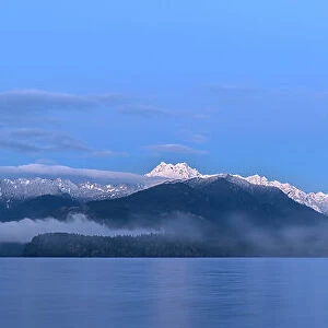 USA, Washington State, Seabeck. Panoramic of moon setting over Olympic Mountains and Hood Canal. Date: 29-01-2021