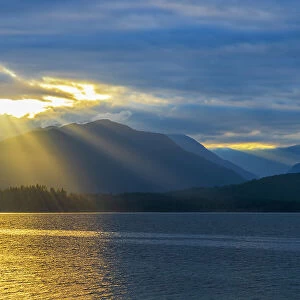 USA, Washington State, Seabeck. Sunburst over Hood Canal and Olympic Mountains at sunset. Date: 13-09-2021