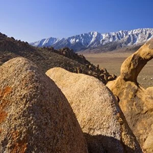 Whitney Portal Arch - rock arch of red granite with snow-capped mountains of the Sierra Nevada behind - Alabama Hills Recreation Area, California, USA