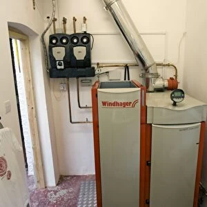 Windhager Austrian wood pellet fired domestic biomass boiler produces heat for thermal store using small wood pellets supplied from a large external hopper installed in small cottage Cotswolds UK