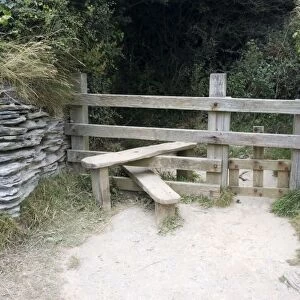 Wooden stile with dog gate between stone walls on cliff path North Devon UK