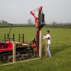 Workman driving timber posts into ground for new post and rail field fence with dedicated Kubota Protech tracked Post Rammer - Cotswolds - UK