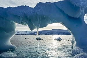 Antarctica, Icicles hang from arched iceberg