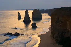 Twelve Apostles sunset - setting sun over the sandstone rock formations of famous Twelve Apostels, which are sculpted by the relentless sea. The force of the sea eats more and more of the rocks away and finally forces them to collapse