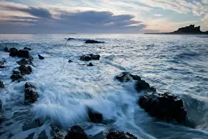 Bamburgh Castle - waves on rocky coastline before the castle - at dawn - Northumberland - England
