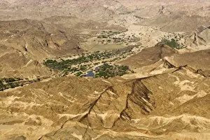 Dyke Prints: Black dolerite dykes spread through the Moon Valley Landscape - The Swakop River with its green foliage leads off into