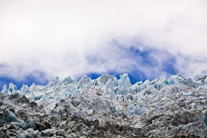Blue glacial ice against sky and clouds