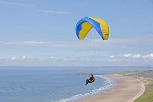 Blue & yellow paraglider - gliding over beach