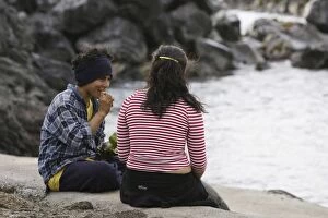 A boy and girl sitting by the sea eating O£urantoOA┬¼