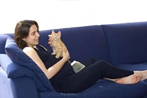 Cat - girl holding ginger kitten on sofa Lady is pregnant