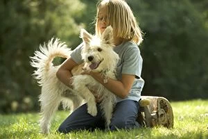 Child playing with white shaggy mongrel dog
