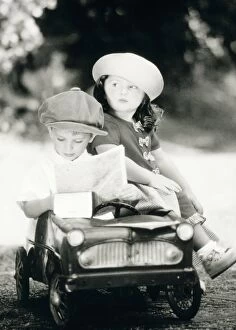 Boys Gallery: Children - boy and girl in toy car reading map