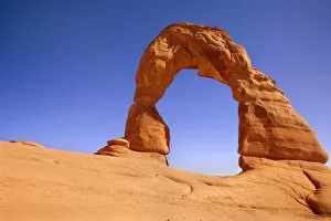 Delicate Arch - delicately sculptured sandstone arch standing on a slickrock slope. In late evening