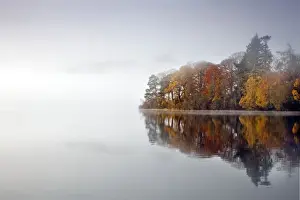 Derwent Water - autumn colours reflected in water of derwent island in the mist with catsbells just visable through the mist - Lake District - England