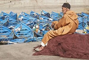 Elderly man resting on heap of fishing nets and