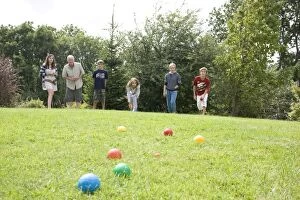 Family playing boule on lawn with coloured plastic balls
