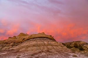 Fiery sunrise clouds over badlands at dawn