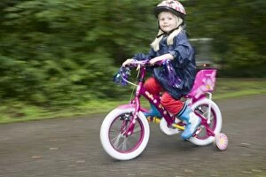 Girl aged four wearing cycle helmet riding brightly