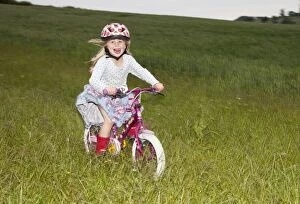 Girl enjoying cycling fast on farm field
