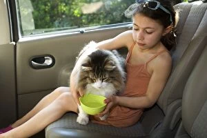 Girl - giving cat a drink - in rear of car
