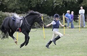 Girl in running race with black pony in mid air - Gymkhana