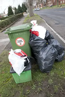 Green wheelie bin overflowing with domestic rubbish awaiting collection Cheltenham UK