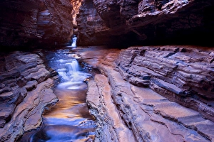 Hancock Gorge - a stream is flowing down Hancock Gorge, surrounded by steep, red and very terraced cliffs