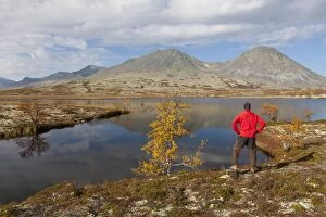 Hiker at a lake in the valley Doraldalen Rondane