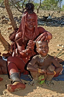 Himba lady - shaving boys head with sheath knife
