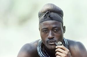 Bushmen Gallery: Himba man smoking a pipe - the head scarf indicates