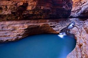 Hancock Gorge - a stream is flowing down Hancock Gorge, surrounded by steep, red and very terraced cliffs