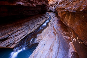 Hancock Gorge - a stream is flowing down Hancock Gorge, surrounded by steep, red and very terraced cliffs