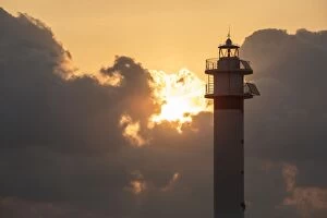 Punta Gallery: Lighthouse at sunrise with the sun behind the clouds